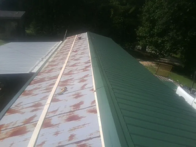 Old rusted panels beside newly installed green metal roofing — Wind Damage Roof Repair by Roofing Brothers in Mosby