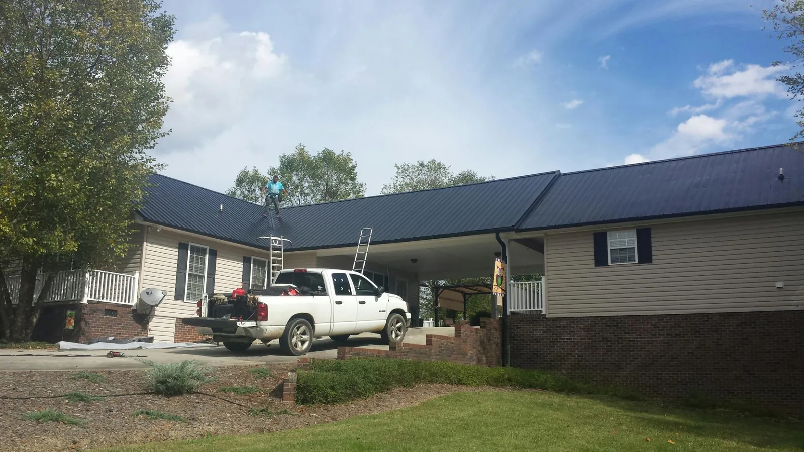 Black metal roof over a home and attached breezeway with ladders set in Mosby