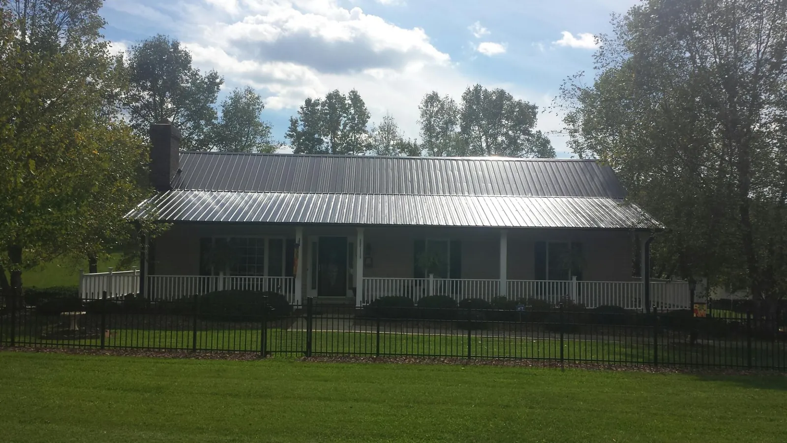 Gray metal roof on a brick ranch with a full width front porch — Gutter Guard Installation work by our crew in Mosby