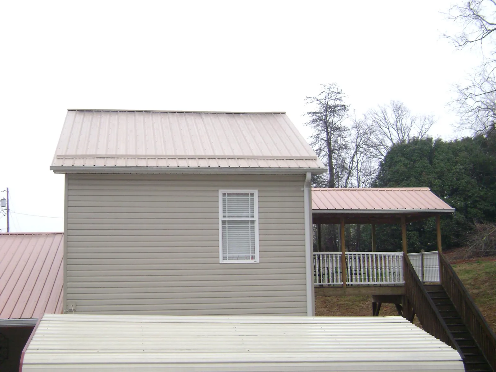 Tan metal roofs on a two story addition and attached porch, from a Roof Replacement job in Mosby